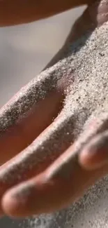 Close-up of sand resting on hands in mobile wallpaper.