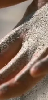 Sand flowing over a hand mobile wallpaper.