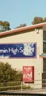 High school building with a sign and trees against a clear sky.