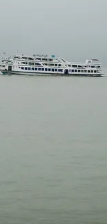 A boat sails in calm sea under an overcast sky.