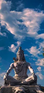 Majestic Lord Shiva statue under a blue sky with clouds.