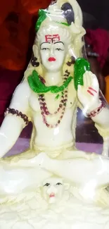 Cream colored Shiva figurine with vivid accents on a decorative background.