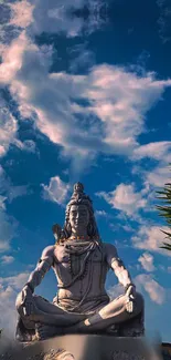 Statue of Shiva against a vibrant blue sky with clouds.