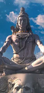 Statue of Shiva meditating under a blue sky.