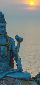 Lord Shiva statue at sunset by the ocean.