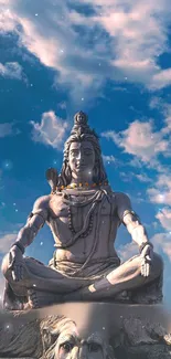 Lord Shiva statue under a blue sky with clouds.