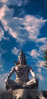Shiva statue under a vibrant blue sky with clouds.