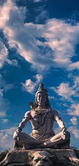 Statue of Lord Shiva under a vivid blue sky with clouds.