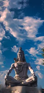 Statue of Lord Shiva meditating under a blue sky with clouds.