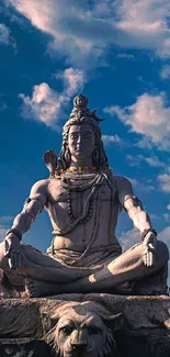 Shiva statue under vibrant blue sky with lush greenery.