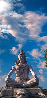 Statue of Shiva under a blue sky with clouds.