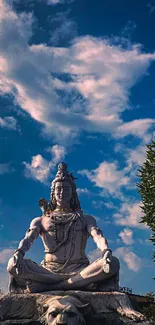 Serene Shiva statue under a vibrant blue sky with fluffy clouds.