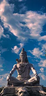 Majestic Shiva statue under a vibrant blue sky with clouds.