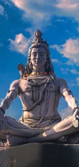 A serene Shiva statue under a bright blue sky with clouds.