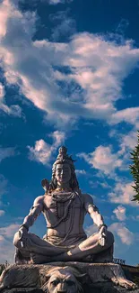 Shiva statue under a vibrant blue and cloudy sky, surrounded by greenery.