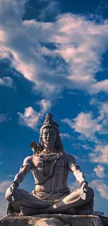 Shiva statue meditation under a vibrant blue sky with soft clouds.