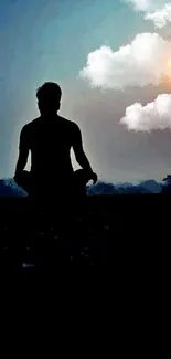 Silhouette meditating at sunset with dark blue background