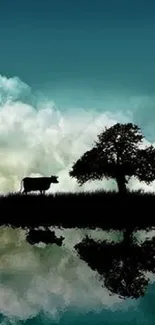 Silhouette of a cow and tree against a turquoise sky and reflective water.