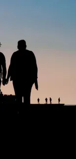 Silhouette of people against a serene sunset on a mobile wallpaper.