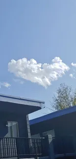 Blue sky with a fluffy white cloud and building view.