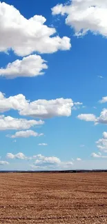 A vast blue sky with fluffy white clouds over a peaceful open field.