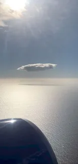 Aerial view of a serene sky and ocean with a cloud and sunlight rays.