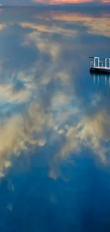 Serene reflection of sky on calm water with distant structure.