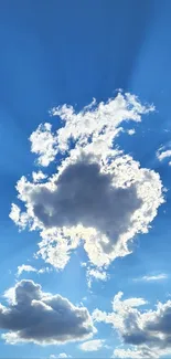 Blue sky with radiant sunbeams and fluffy clouds above a horizon.