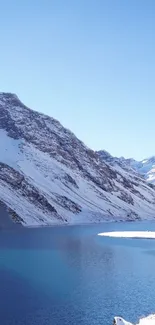 Snowy mountain overlooking a tranquil blue lake.