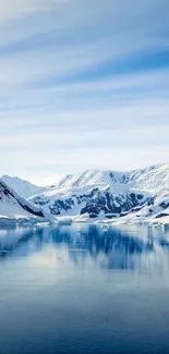 Snowy mountain reflecting in blue water under a clear sky.