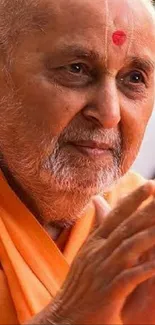 Serene portrait of elderly man in orange robe with a peaceful expression.