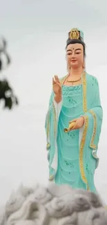 Serene statue in turquoise robes standing against a calm background.