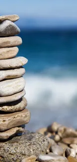 Stacked stones by a blue ocean on a serene beach.