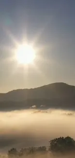 Sunrise over misty hills with fog and glowing sun in a tranquil landscape.