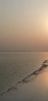 Serene sunset over a calm beach with warm colors and glowing horizon.