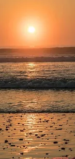 Serene beach at sunset with warm orange glow.