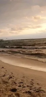 Calm beach at sunset with waves and cloudy sky.