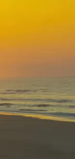 Beautiful sunset over a serene beach with calm waves and orange sky.