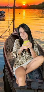 Woman in a boat at sunset with orange sky reflecting on water.