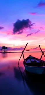 Calm boat in a vibrant purple and pink sunset reflected on the water.