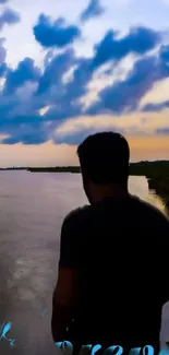 Silhouette by river at sunset with a dramatic sky.