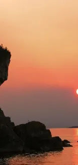 Sunset over a serene cliffside with orange skies.