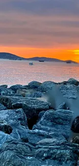 Serene coastal sunset with rocky shore and vibrant orange sky.