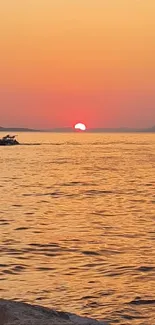 Sunset over the ocean with rocky shore and vibrant sky hues.