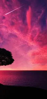 Vibrant purple sunset with silhouetted tree over ocean.