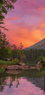 Serene sunset over forested lake with vibrant pink sky.