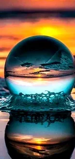 Crystal globe reflecting sunset over ocean waves.