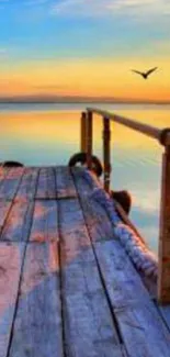 Serene sunset over a calm lake with a wooden pier and birds flying.