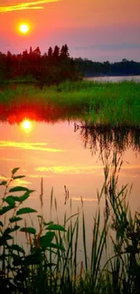 Vibrant sunset over a serene lake with reflections and lush greenery.