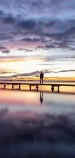 Serene sunset over a calm lake with a silhouetted person and reflections.